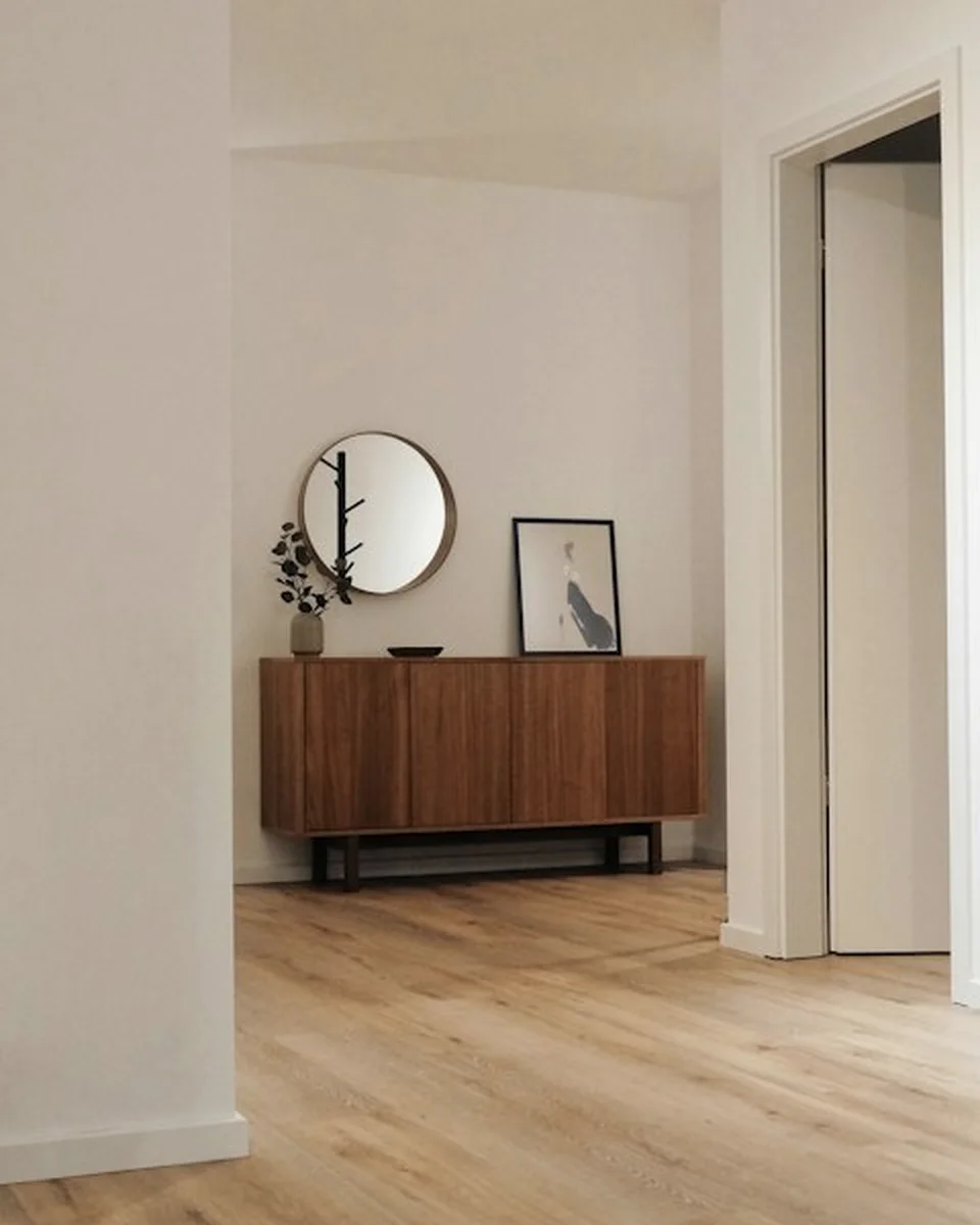 Quiet hallway with timber console, framed artwork and warm plastered walls
