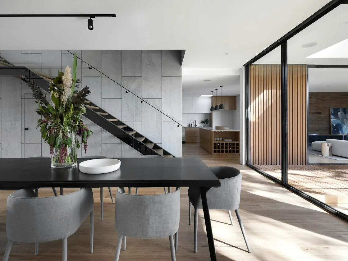 Urban apartment dining area with dark staircase and framed glazing