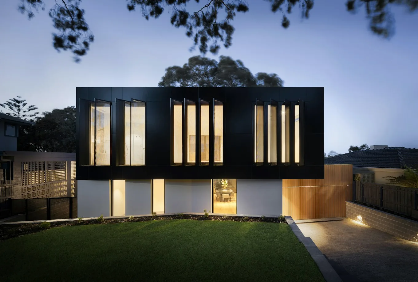 Contemporary coastal residence with dark timber cladding and evening light