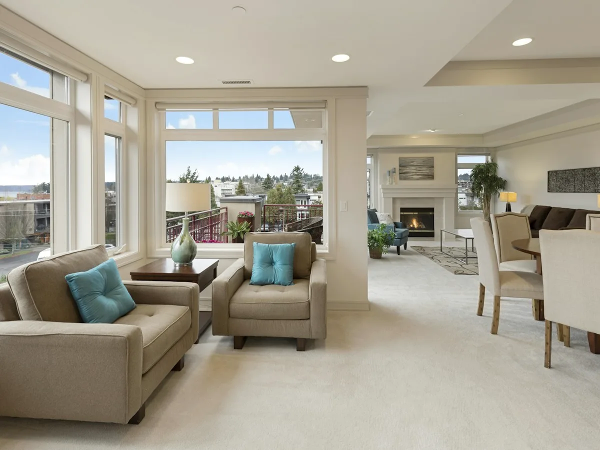 Light apartment living area with panoramic glazing and neutral seating